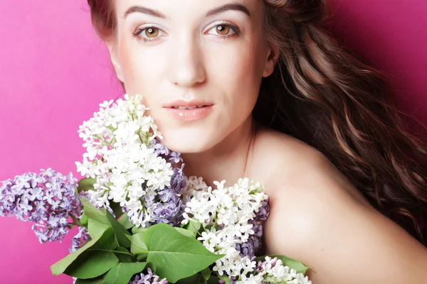 Menina com flores lilás sobre fundo rosa — Fotografia de Stock