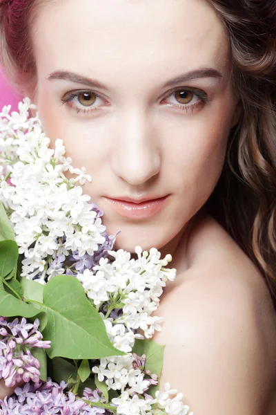 Meisje met lila bloemen over roze achtergrond — Stockfoto