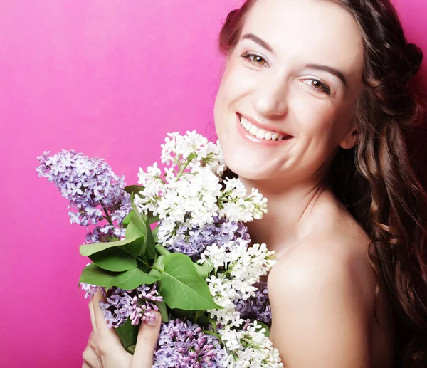 Meisje met lila bloemen over roze achtergrond — Stockfoto