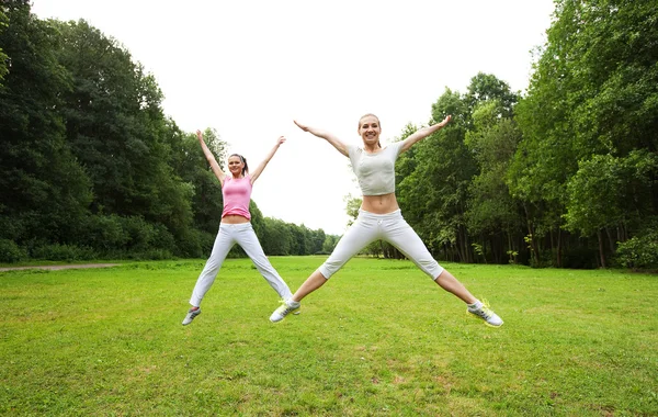 Duas meninas saltam no parque de verão . — Fotografia de Stock