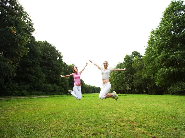 Dos chicas jóvenes saltan en el parque de verano . — Foto de Stock