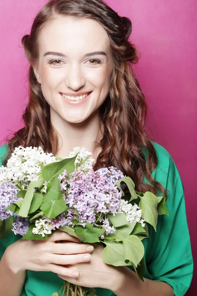 Menina com flores lilás sobre fundo rosa — Fotografia de Stock