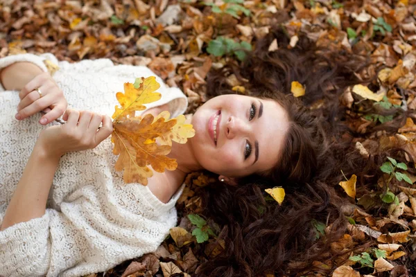 Femme allongée sur des feuilles d'automne, portrait extérieur — Photo