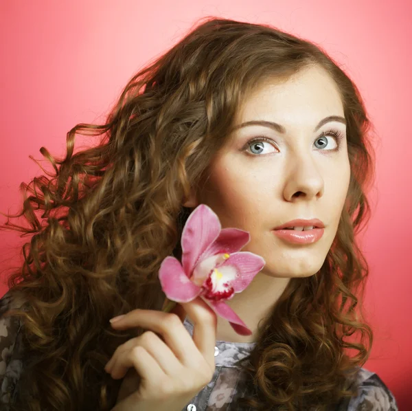 Kvinna med orkidé blomma över rosa bakgrund — Stockfoto