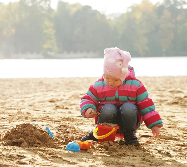 Dziewczynka gra z piasku na plaży jesień — Zdjęcie stockowe