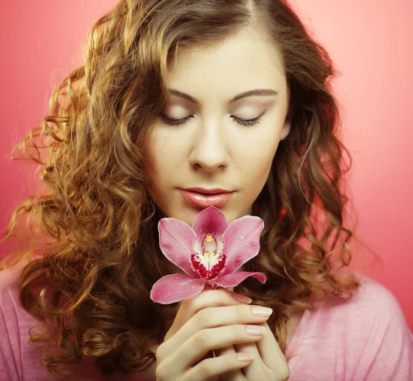 Donna con fiore di orchidea su sfondo rosa — Foto Stock