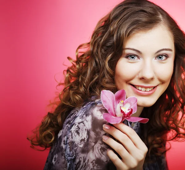 ピンクの背景の上の蘭の花を持つ女性 — ストック写真