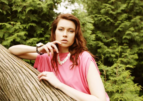 Jeune femme posant sur un arbre — Photo