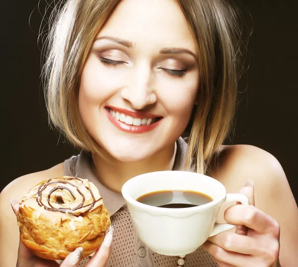 Woman eating cookie and drinking coffee. — Stockfoto