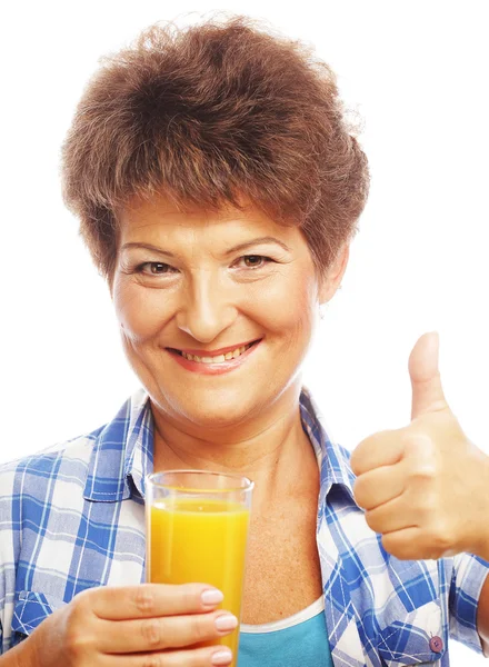 Mulher madura segurando um copo de suco de laranja — Fotografia de Stock