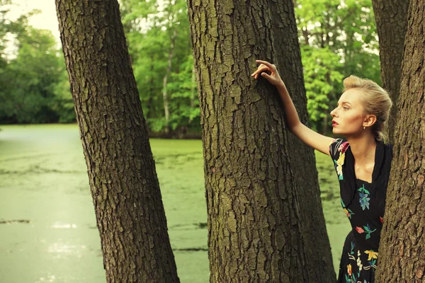 Jeune femme posant sur un arbre — Photo