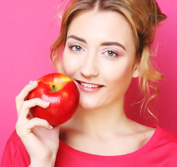 Женщина с яблоком на розовом фоне — стоковое фото