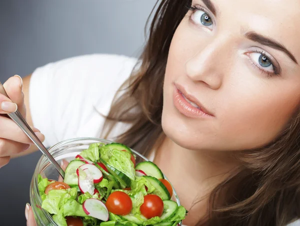 Jong meisje met een salade op een witte achtergrond — Stockfoto