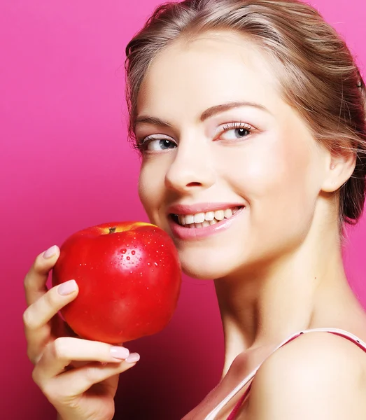 Kvinne med eple over rosa bakgrunn – stockfoto