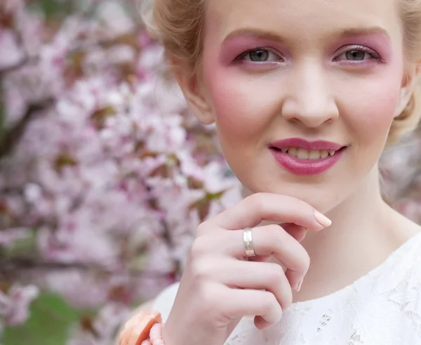 Junge blonde Frau im blühenden Sakura-Garten — Stockfoto