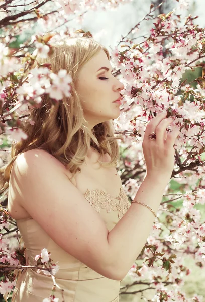 Young blond girl in spring flowers garden — Stock Photo, Image