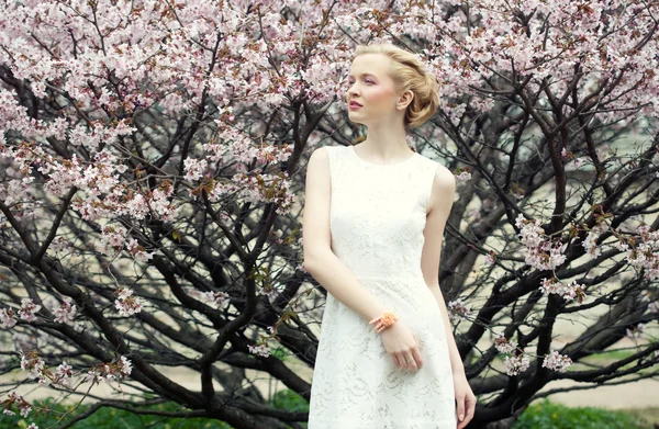 Menina loira jovem no jardim de flores de primavera — Fotografia de Stock