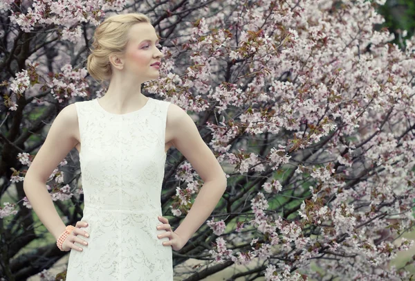 Menina loira jovem no jardim de flores de primavera — Fotografia de Stock