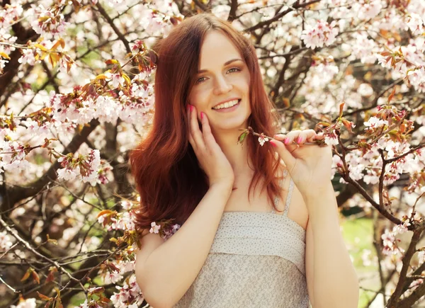 Heureuse jeune femme dans le jardin de fleurs de printemps — Photo