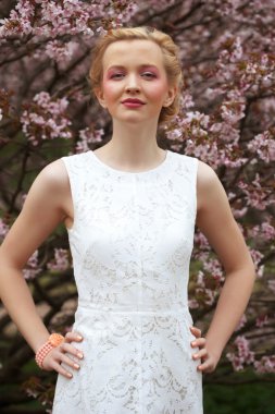 Bahar çiçeklerinin bahçesindeki sarışın genç kız.