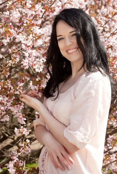 Glückliche junge Frau im Frühlingsblumengarten — Stockfoto