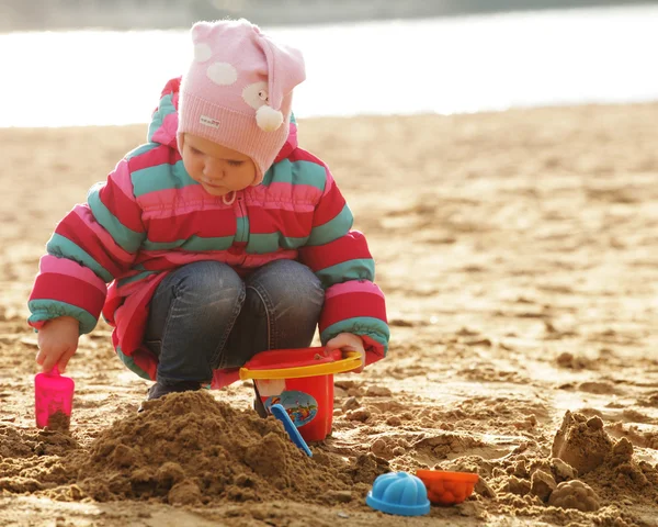 Petite fille jouant avec le sable à la plage d'automne — Photo