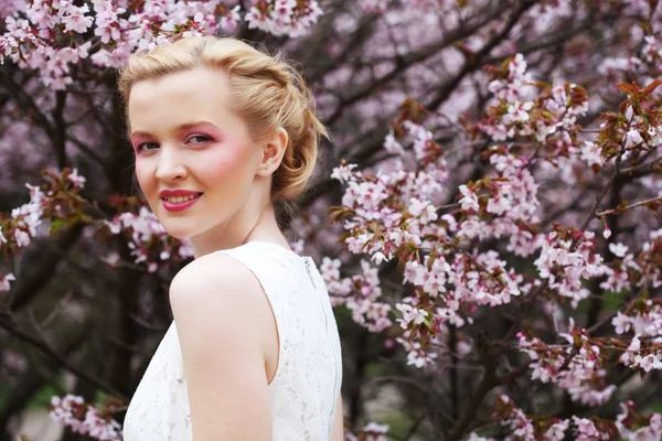 Mulher cheirando flores no jardim florescendo sakura — Fotografia de Stock