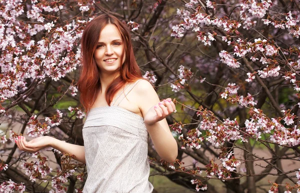 Heureuse jeune femme dans le jardin de fleurs de printemps — Photo