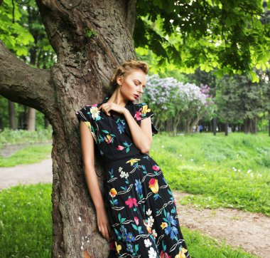 Genç bir kadın ağaçta poz veriyor.