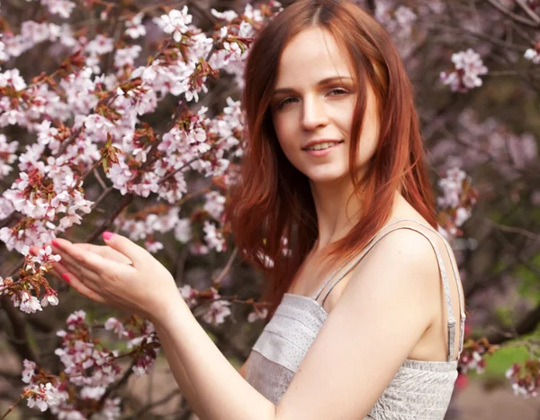 Glückliche junge Frau im Frühlingsblumengarten — Stockfoto