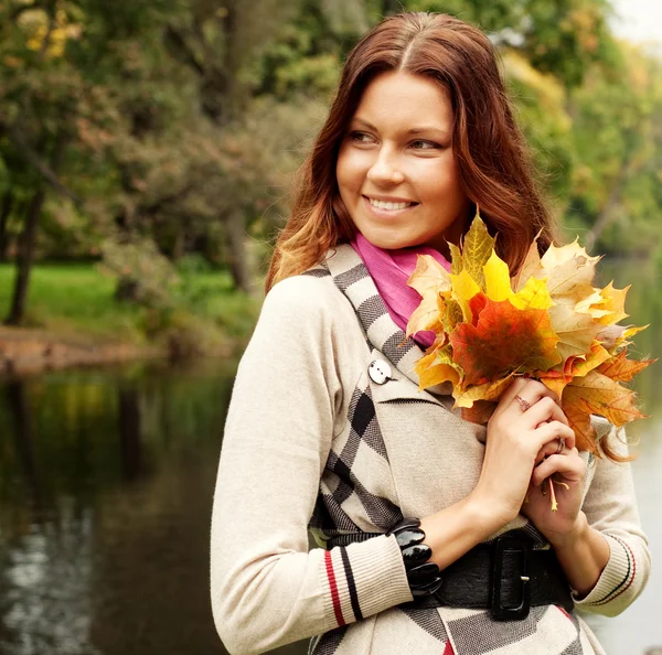 Młoda kobieta z jesiennymi listkami w parku — Zdjęcie stockowe