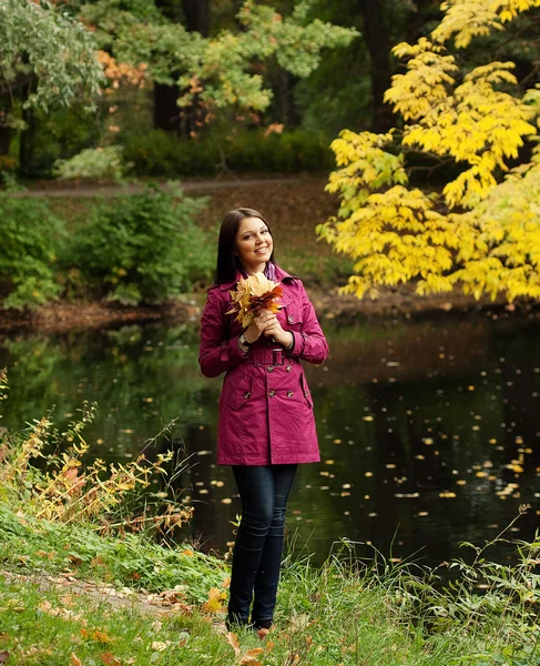 Giovane donna con foglie autunnali nel parco — Foto Stock