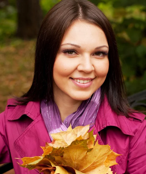 Tyylikäs nainen syksyn lehdet istuu penkillä — kuvapankkivalokuva