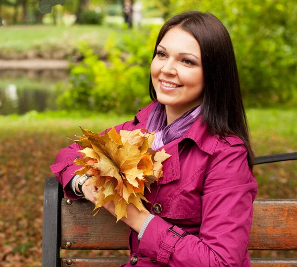 Mujer joven y elegante con hojas de otoño — Foto de Stock