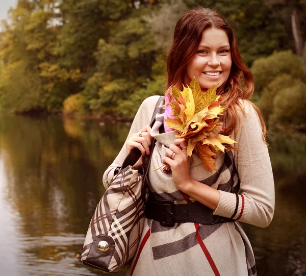 Jonge vrouw met herfstbladeren in park — Stockfoto