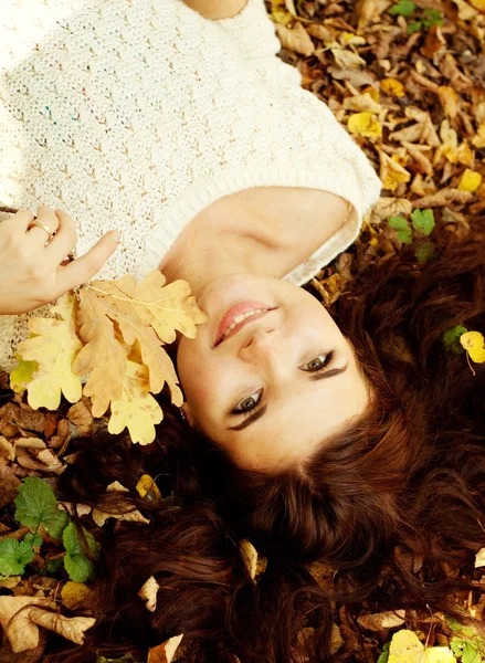 Mujer acostada sobre hojas de otoño, retrato al aire libre —  Fotos de Stock