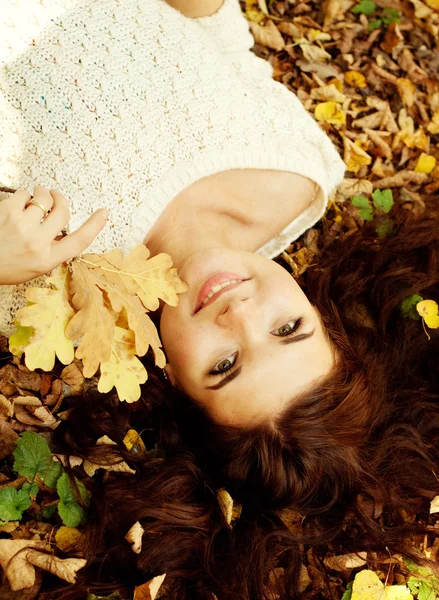 Femme allongée sur des feuilles d'automne, portrait extérieur — Photo