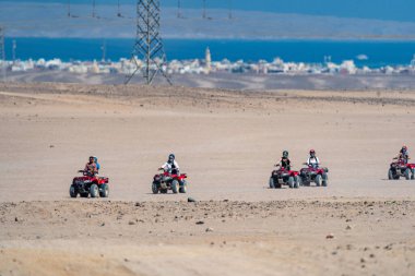 Hurghada şehrinden çok uzak olmayan Arap çölünde safari gezisi sırasında dört tekerli bisiklet kullanan insanlar.