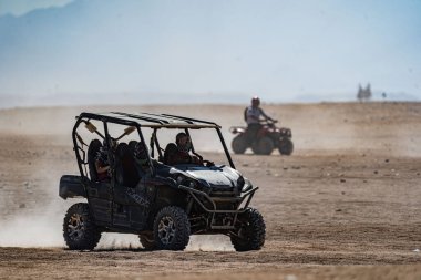 Hurghada şehrinden çok uzak olmayan Arap çölünde safari gezisi sırasında dört tekerli bisiklet kullanan insanlar.