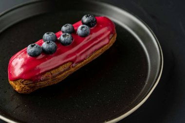 Tatlı, siyah arka planda siyah servis tabağına doldurulmuş küçük bir börek turtasıdır. Kesilmiş bir parça kek.