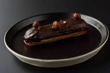 Tatlı, siyah arka planda siyah servis tabağına doldurulmuş küçük bir börek turtasıdır. Kesilmiş bir parça kek.