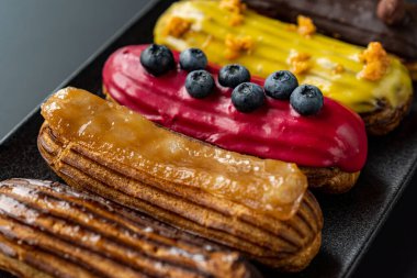 Tatlı, siyah arka planda siyah servis tabağına doldurulmuş küçük bir börek turtasıdır. Kesilmiş bir parça kek.