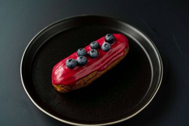 Tatlı, siyah arka planda siyah servis tabağına doldurulmuş küçük bir börek turtasıdır. Kesilmiş bir parça kek.