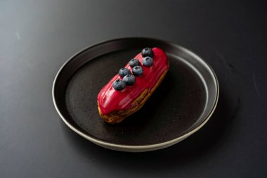 Tatlı, siyah arka planda siyah servis tabağına doldurulmuş küçük bir börek turtasıdır. Kesilmiş bir parça kek.