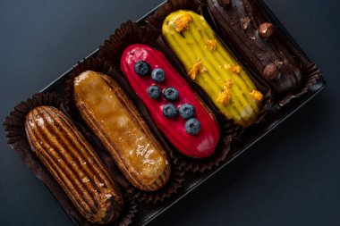 Tatlı, siyah arka planda siyah servis tabağına doldurulmuş küçük bir börek turtasıdır. Kesilmiş bir parça kek.