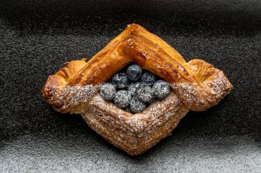 Tatlı, siyah arka planda siyah servis tabağına doldurulmuş küçük bir börek turtasıdır. Kesilmiş bir parça kek.
