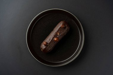 Tatlı, siyah arka planda siyah servis tabağına doldurulmuş küçük bir börek turtasıdır. Kesilmiş bir parça kek.