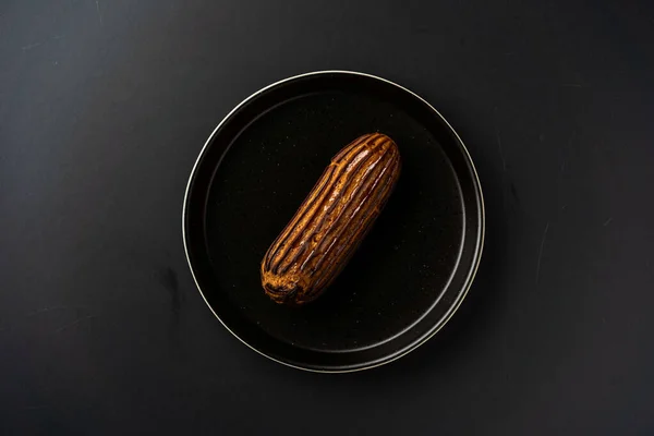 Sobremesa é uma pequena torta de massa folhada com recheio dentro de uma placa de serviço preta em um fundo preto. Um pedaço de bolo com um corte — Fotografia de Stock