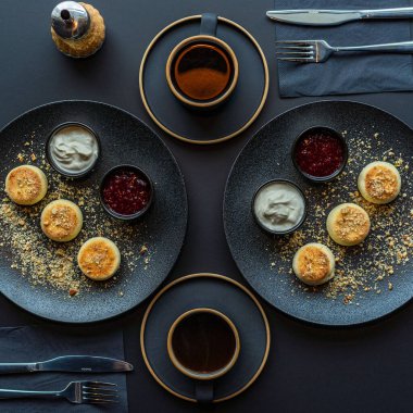 Ekşi kremalı ve reçelli siyah tabakta süzme peynirli kek.