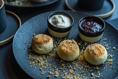 Ekşi kremalı ve reçelli siyah tabakta süzme peynirli kek.